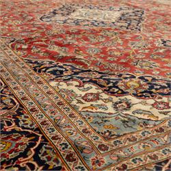 Persian Kashan carpet, the field in rich rust tone centred by an ivory and blue medallion with palmette extensions, surrounded by intricate foliate arabesques and stylised blooms, within triple floral borders incorporating palmettes and interlaced tendrils, woven in the region of Kashan