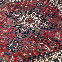 North West Persian Heriz carpet, the red ground field with large star medallion surrounded by stylised plant motifs, ivory ground spandrels with stylised leaf decoration, repeating guarded border