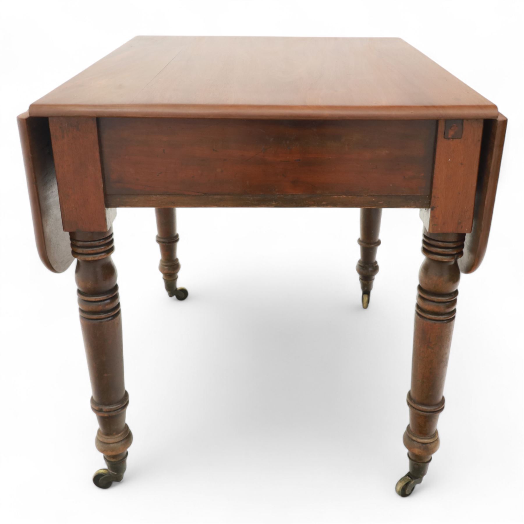 Mahogany drop-leaf Pembroke table circa 1900, with rounded rectangular top and single frieze drawer, raised on turned and tapered supports with brass castors (Extended 128cm)