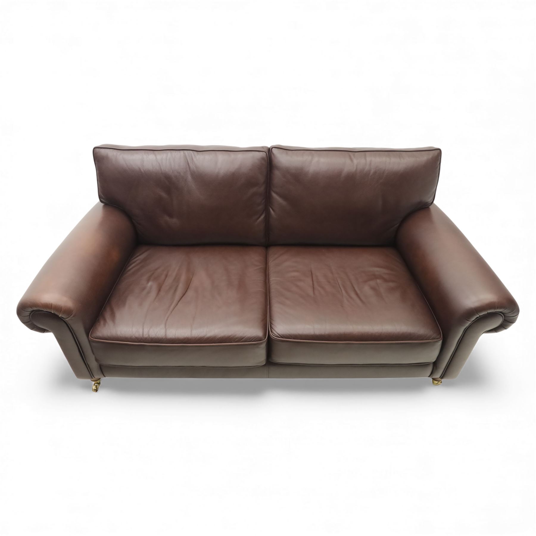 Laura Ashley - brown leather two seater sofa, loose cushion back and seat, flanked by scrolled arms upon light stained wood supports on castors