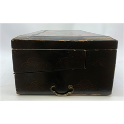  A 20th century Chinese black lacquer and gilt detailed writing box, decorated with figures, pagodas and cranes amidst a mountainous landscape, the hinged cover opening to reveal a compartmented interior and fold out baize lined slope, H20cm L46.5cm D31.5cm.   