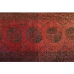 Antique Persian Bokhara red ground runner rug, repeating Gul pattern, surrounded by borders, with fringed ends