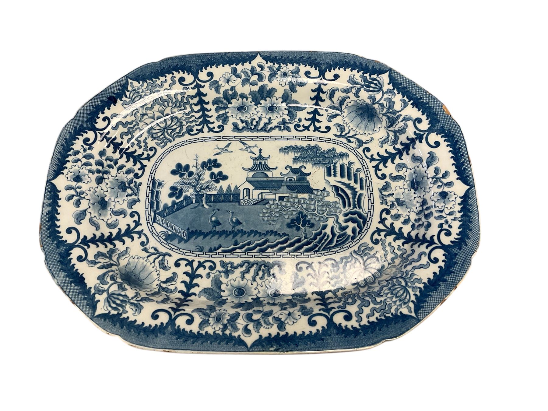 19th century English blue and white meat platter, of shaped oblong form, decorated with a central scene of birds within a fenced garden with pavilion and trees, within a wide border of stylised oriental flowers, and fine cell bordered rim, W52cm