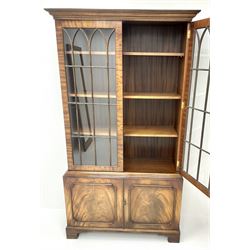 20th century mahogany bookcase, projecting cornice, two doors enclosing three adjustable shelves above two cupboards, bracket supports 