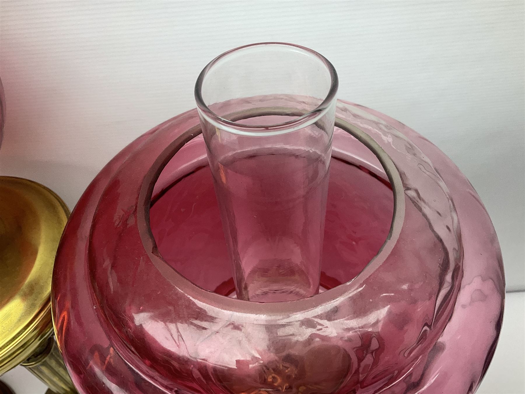 Victorian cast brass oil lamp, with fluted pink glass shade, together with two smaller brass oil lamps with pink shades and reservoirs and a pair of oil lamps, the bases modelled as putti, with pink glass reservoir  and frosted shades, tallest H70cm