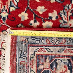Persian crimson ground rug, interlacing floral stems linking ivory palmettes, rosettes and serrated leaves, within a navy floral border flanked by ivory patterned guards