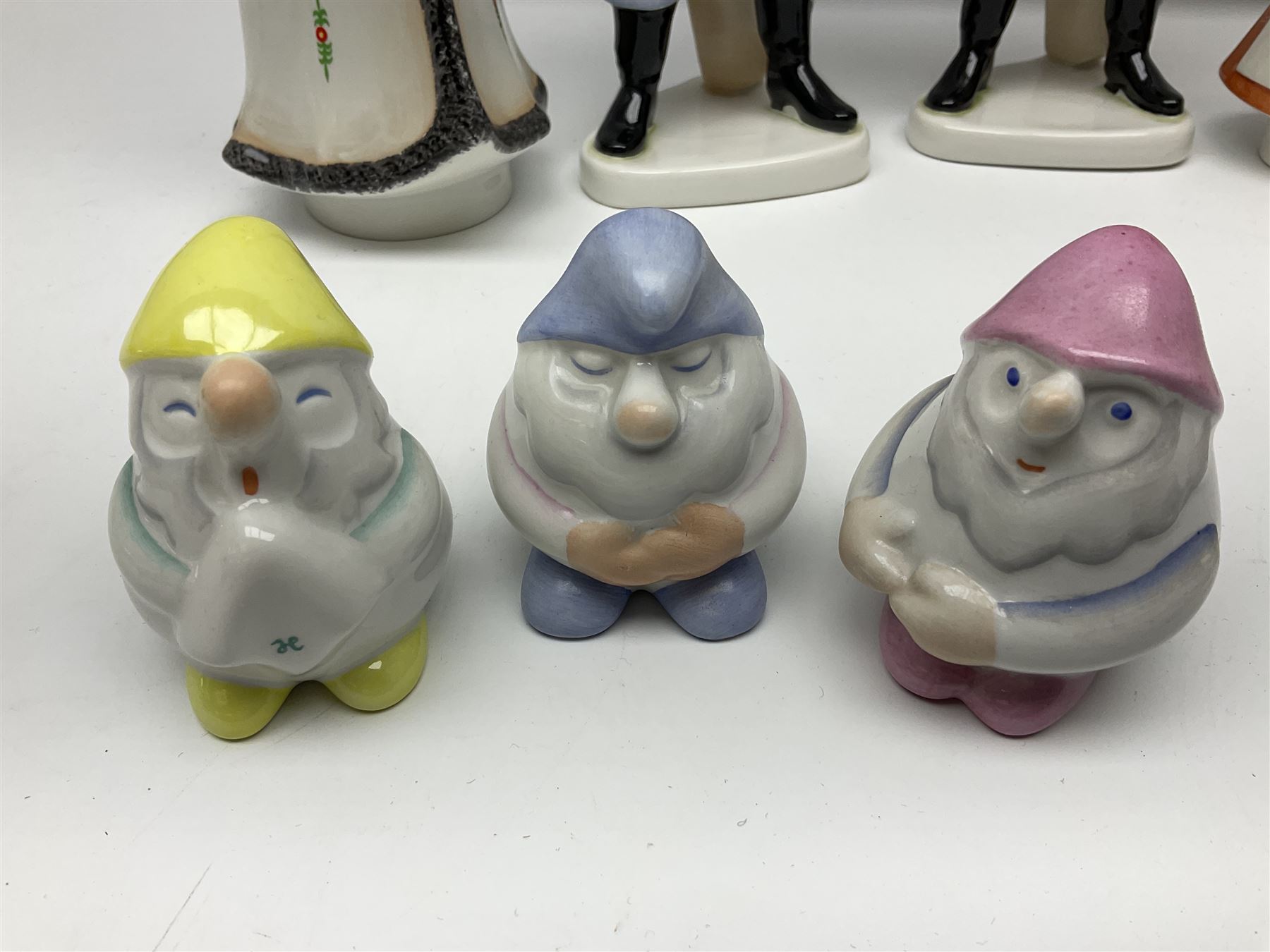 Group of eleven Aquincum of Budapest figures, comprising two of a man in a feather hat, seven dwarves, man and woman in traditional dress, all with printed marks beneath