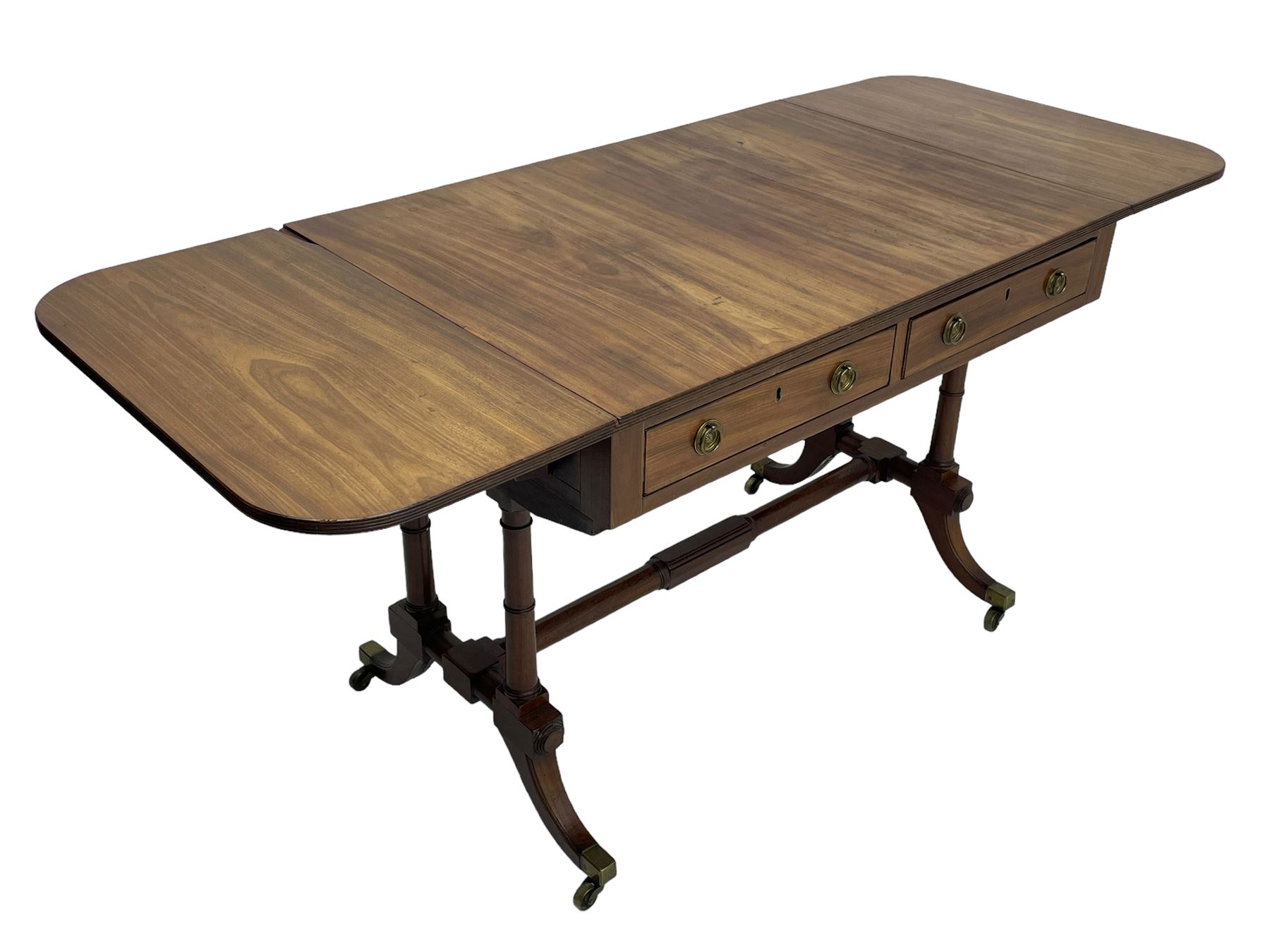 George III mahogany sofa table, rectangular drop-leaf top with reed moulded edge and rounded corners, fitted with two frieze drawers and two opposing false drawers, quadruple collar turned pillar supports on turned and block platforms, splayed and moulded supports with brass cups and castors 