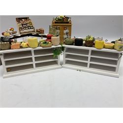 Collection of miniature dolls house grocery shop furniture and produce, comprising glazed corner counter with brass style cash register, shelved preserves unit, pies, cheese board and trays of meats, pair of white cheese counters, biscuit display with six tins, glazed preserves cabinet, pair of shop chairs and four further cheese boards complete with grapes and label flags