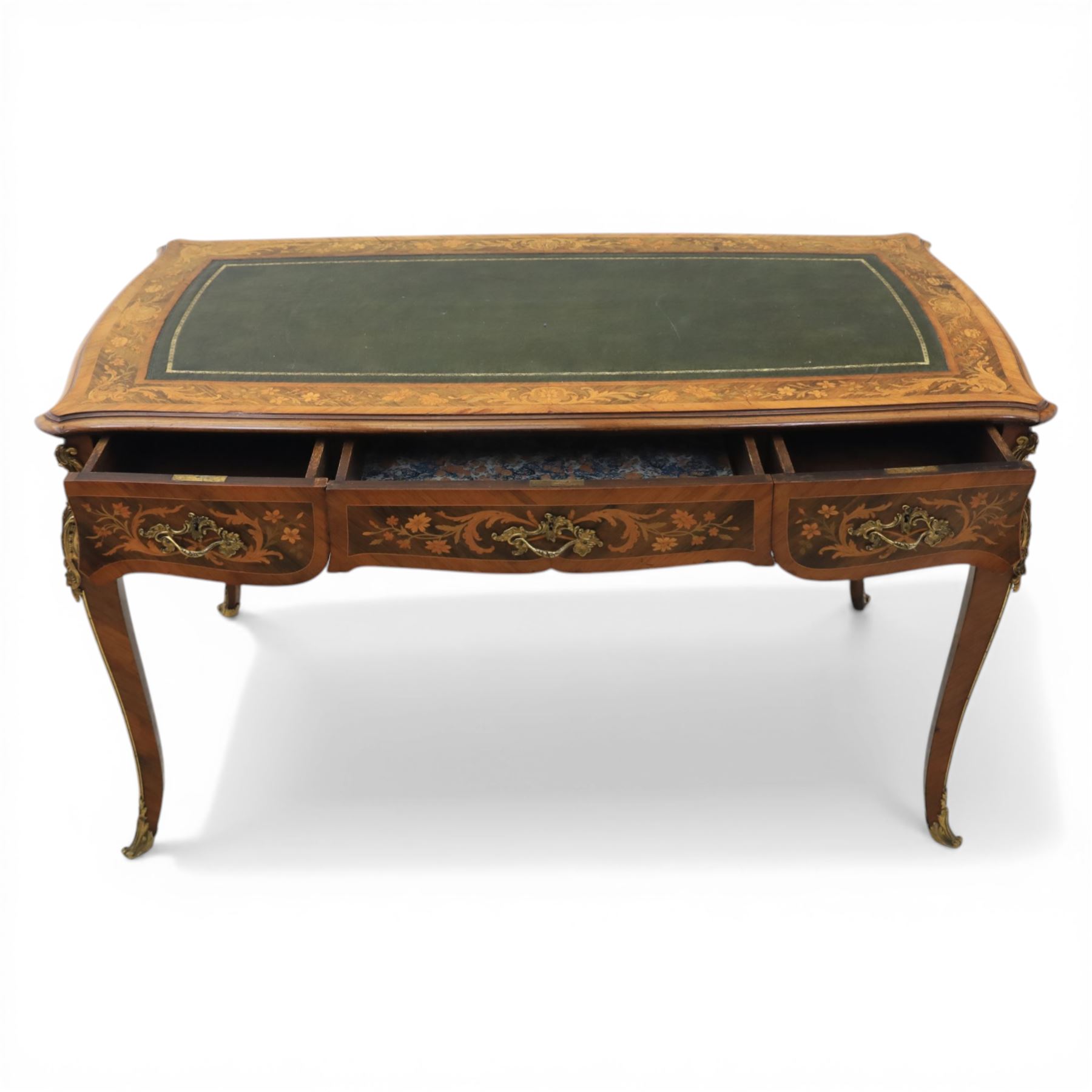 Late 19th century French kingwood and marquetry bureau plat, the serpentine rectangular top with green leather inset writing surface within crossbanded and foliate marquetry border, above a shaped frieze fitted with three drawers with floral marquetry panels and gilt metal handles, upon cabriole supports with applied gilt metal mounts and sabots
