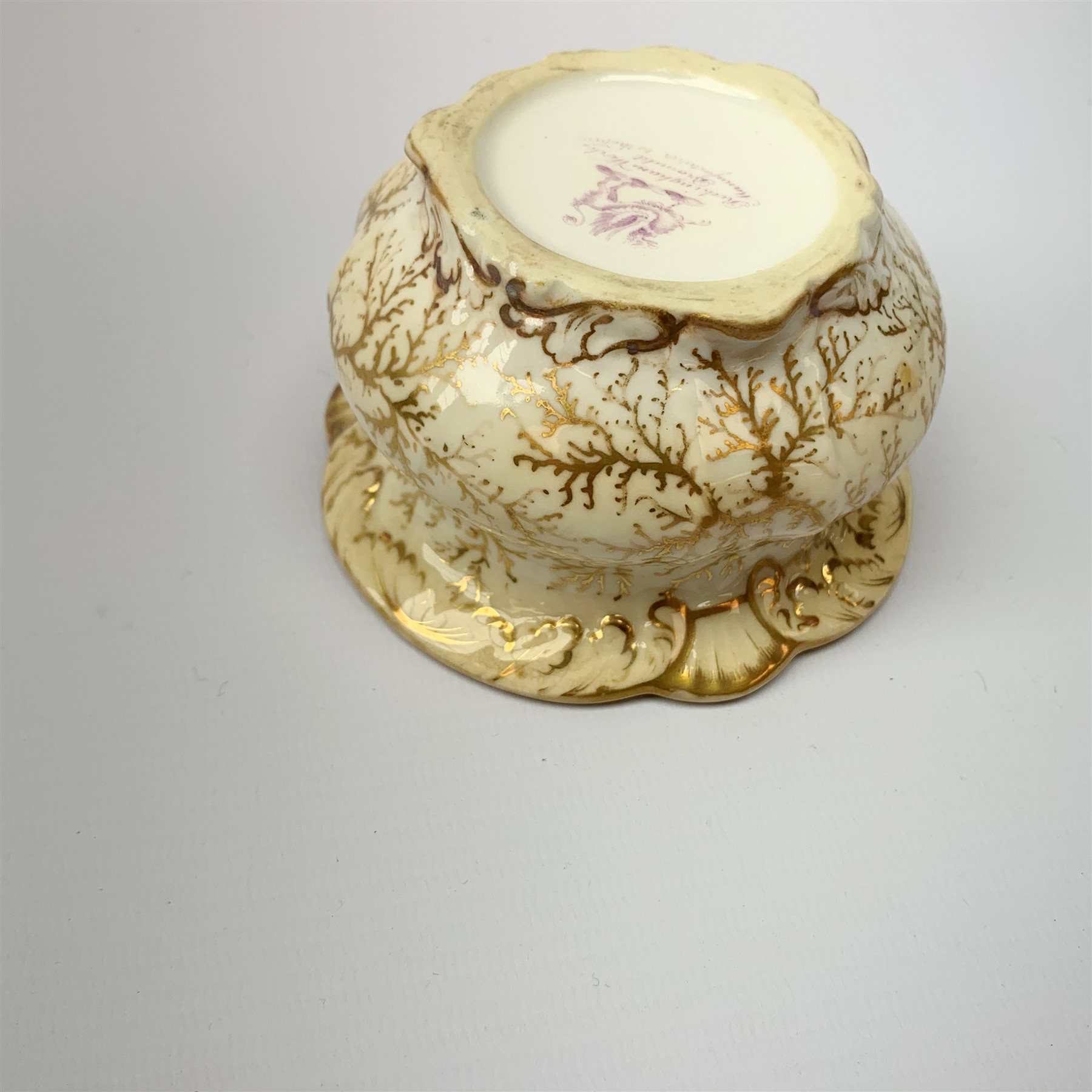 A Rockingham inkwell, with scroll rim, the whole decorated in gilt with a seaweed pattern, with a printed puce mark beneath, D9.5cm. 