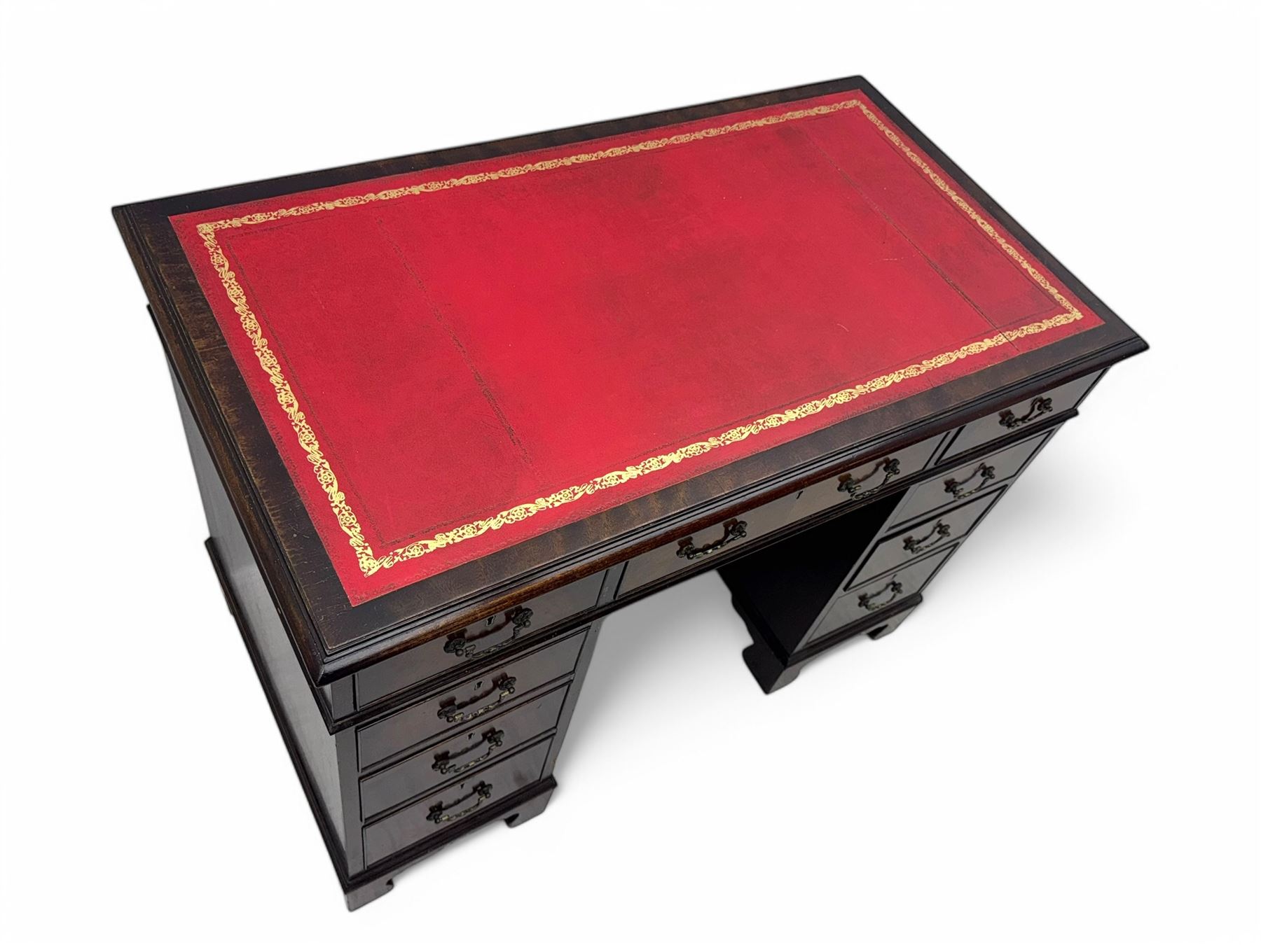 Georgian design mahogany kneehole desk, moulded rectangular top with red gilt-tooled leather writing surface, over an arrangement of nine cock-beaded drawers with brass swan neck handles, on bracket feet