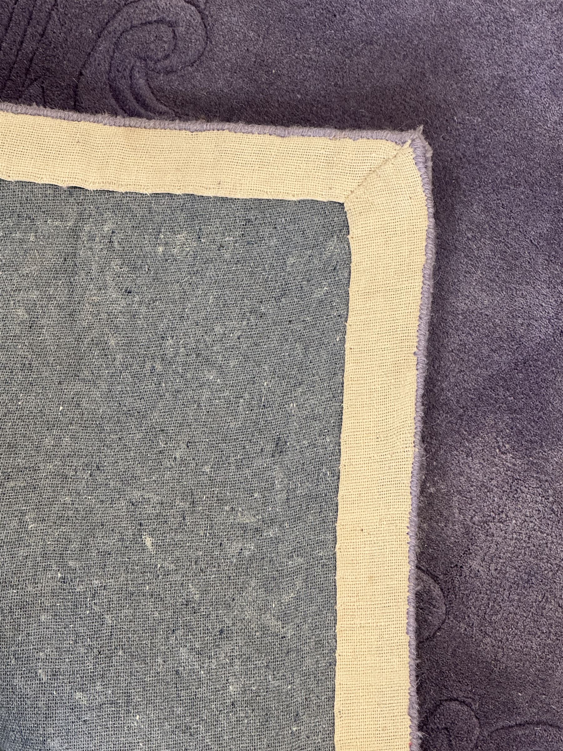 Chinese wool rug, purple ground with tonal floral and foliate pattern, central medallion of stylised flowers, the corners with large rosettes, framed by broad border of scrolling floral and leafy motifs 