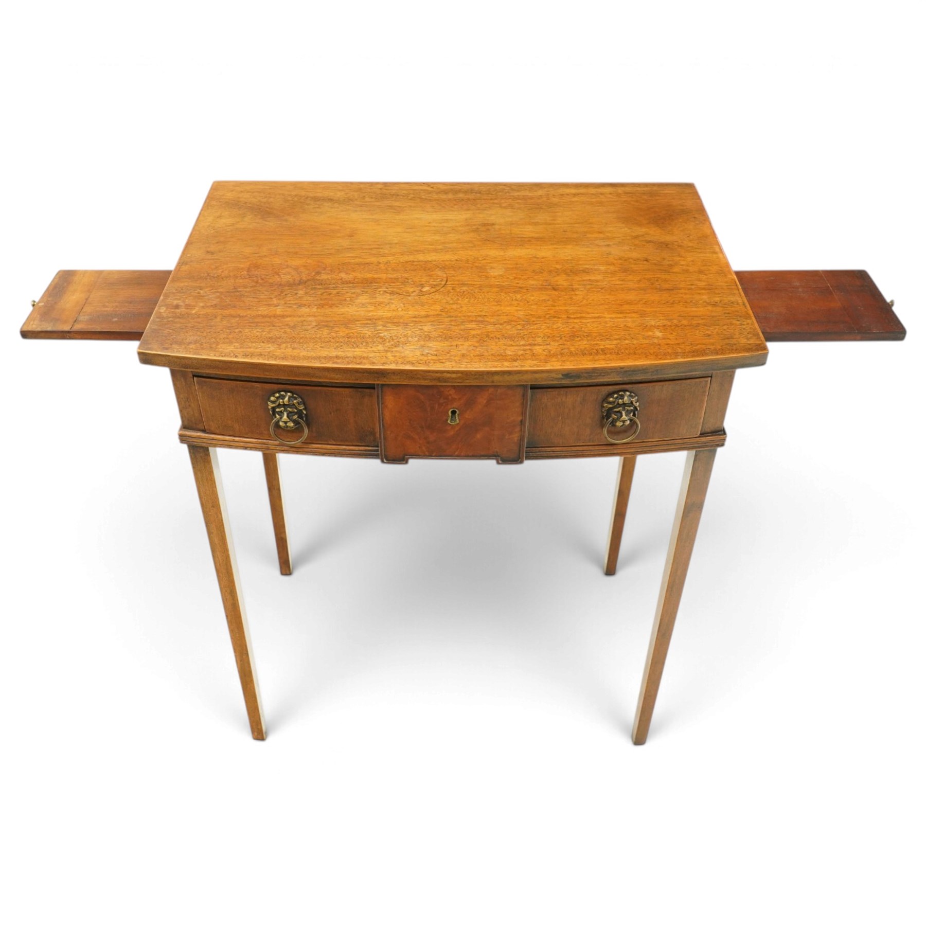 George III mahogany bowfront side table, fitted with single frieze drawer with brass lion-mask handles and twin candle-rests to each side, lower reeded edge on square tapering supports