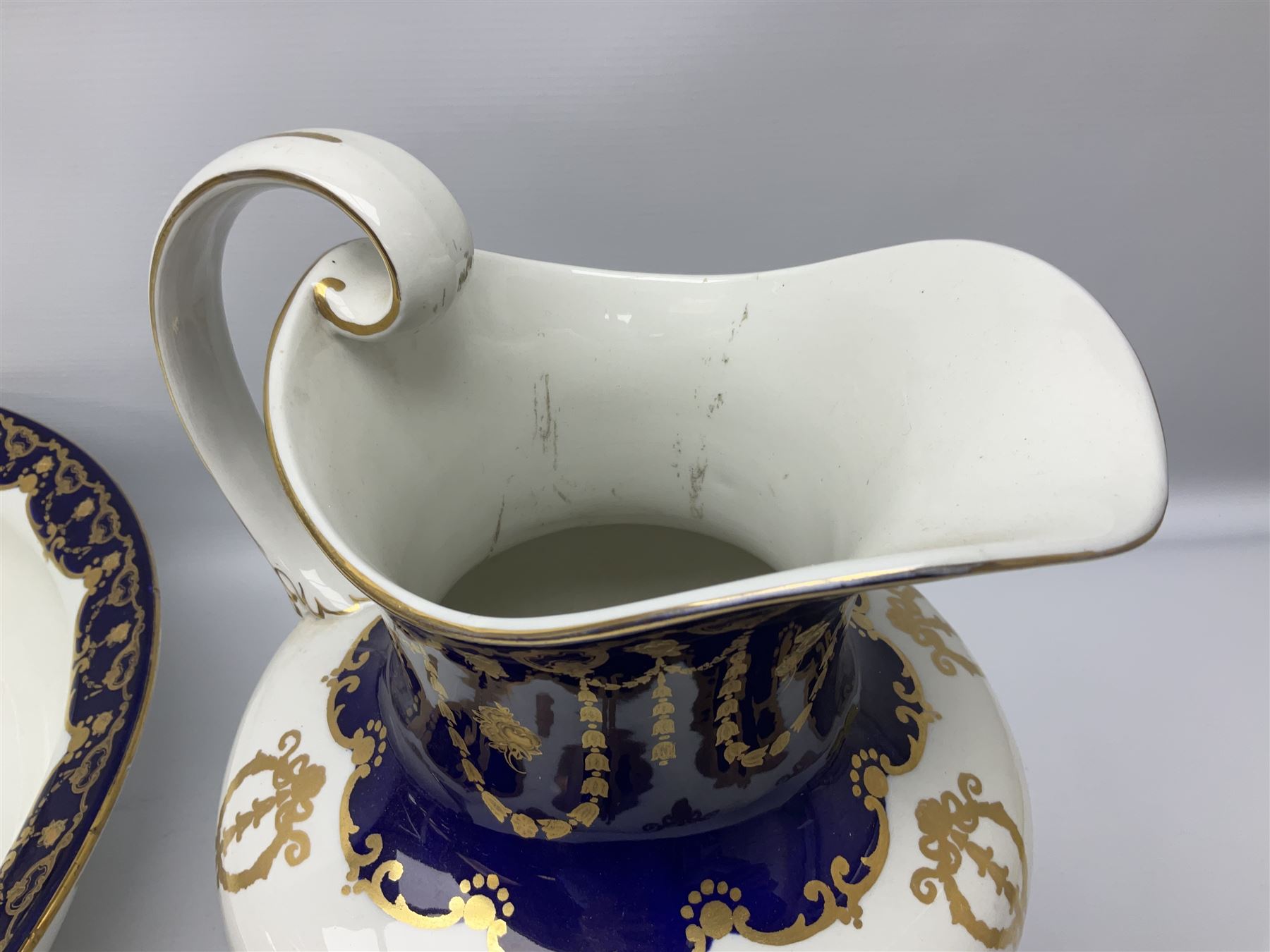 Early 20th century Bishop and Stonier four piece toilet set, comprising washbowl, wash jug, toothbrush pot, and chamber pot, each  decorated with deep blue band and husk swags and festoons in gilt, with printed Caduceus Bisto marks beneath and printed retailers mark 'Manufactured for Harrods Limited London', wash bowl D43cm, wash jug H31.5cm