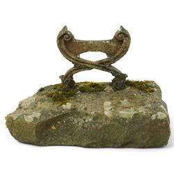 19th century cast iron boot scraper, with scrolled upright mounts, set into a rectangular moss-covered stone base