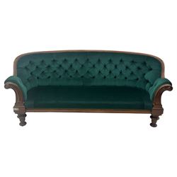 Victorian mahogany settee, upholstered in green buttoned fabric, moulded frame and scroll carved arm terminals, turned supports on castors