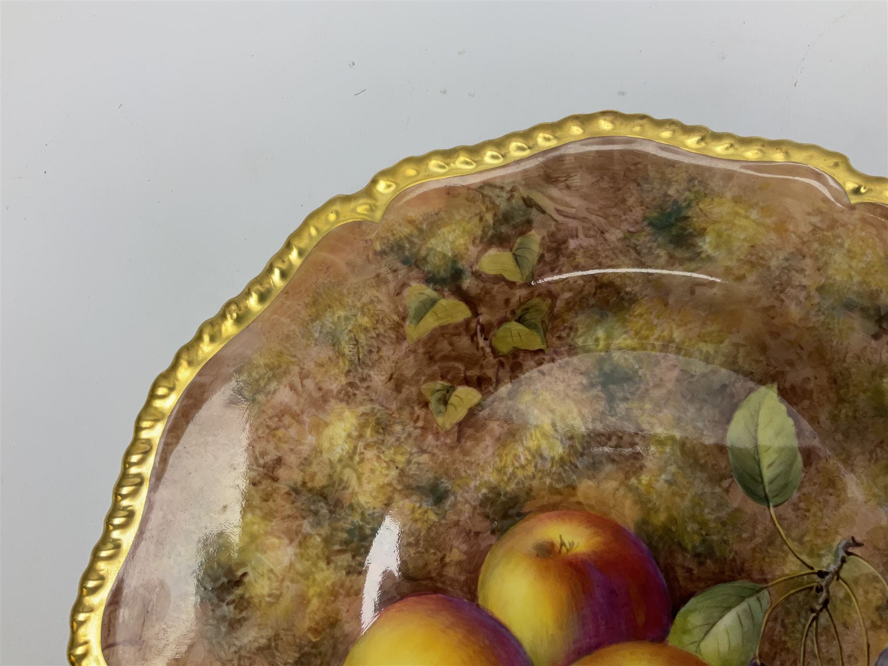 Mid 20th century Royal Worcester cabinet plate decorated by John Freeman, of circular form with gilt shaped rim, hand painted with a still life of fruit upon a mossy ground, signed Freeman, with black printed mark beneath, D27cm
