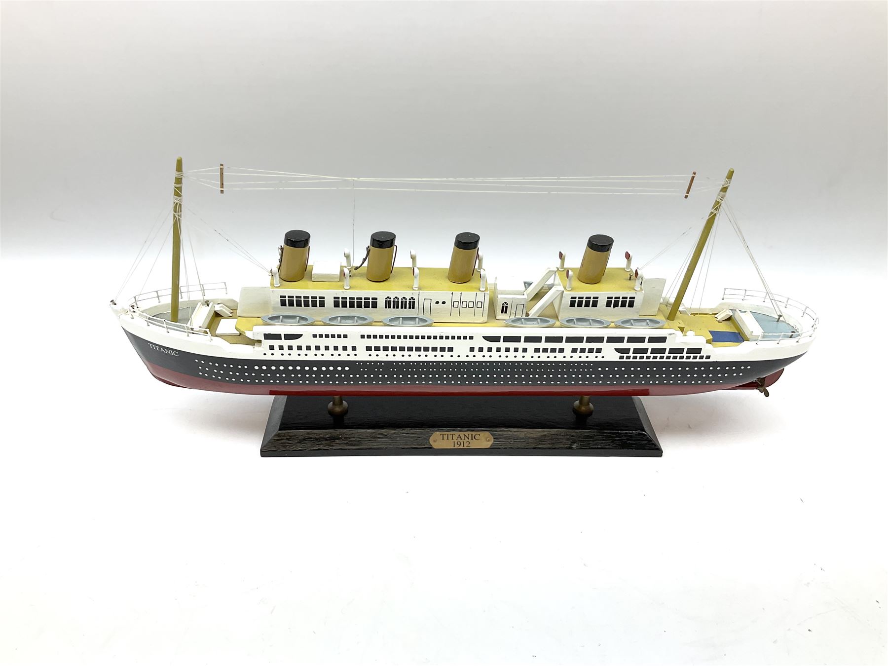 Wooden model of RMS Titanic, on a fixed black stand bearing plaque inscribed 'Titanic 1912', L54cm, H22cm, together with model of a sloop, gaff rigged on stand bearing plaque inscribed 'Sloop' L32cm, H42cm; and model of a fishing trawler on a stand bearing plaque inscribed 'Chalutier' L35cm, H28cm (3)