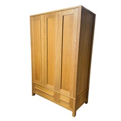 Contemporary light oak triple wardrobe, panelled doors with vertical linear design, left section enclosing hanging rail and single shelf, right section with adjustable shelves, over two drawers, on square stile supports