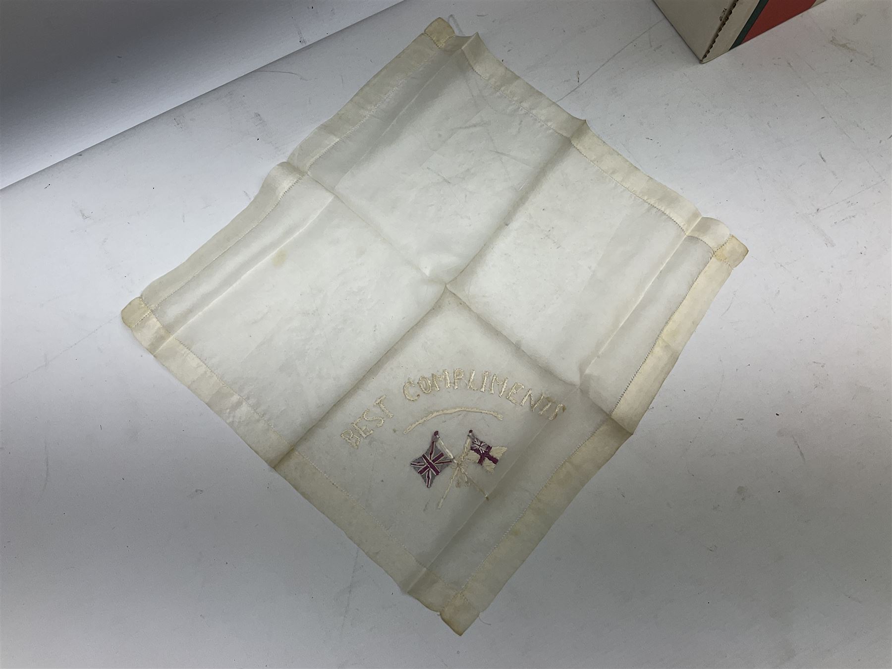 Three WW1 embroidered silk handkerchiefs including RAF & RN; trench art brass napkin ring inscribed 'Arras' and miniature peaked cap with inset 1914 penny; small quantity of cap badges and pips; four reference books on medals and badges etc