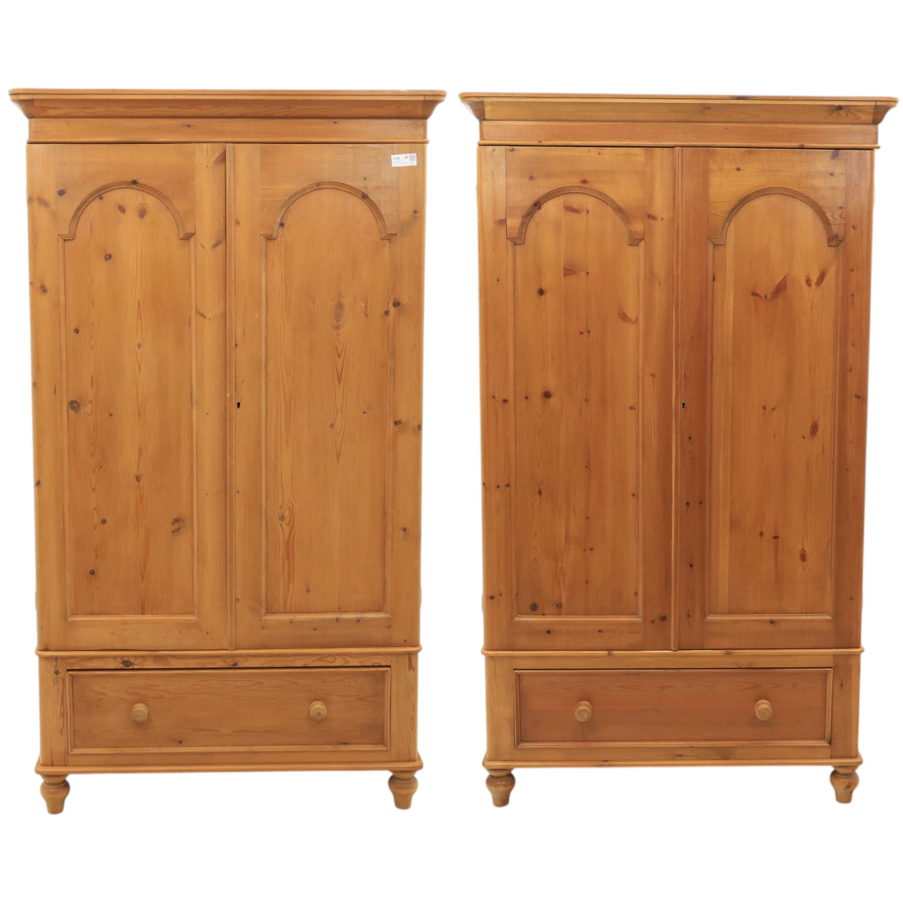 Two contemporary traditional-style wardrobes, projecting plain cornice above two arched moulded panel doors, above a full-width drawer fitted with turned wooden handles, raised on turned bun feet
