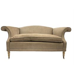 Traditional two seat sofa, curved back over scrolled arms, upholstered in crushed beige fabric with matching loose cushions, on turned front supports with brass and ceramic castors