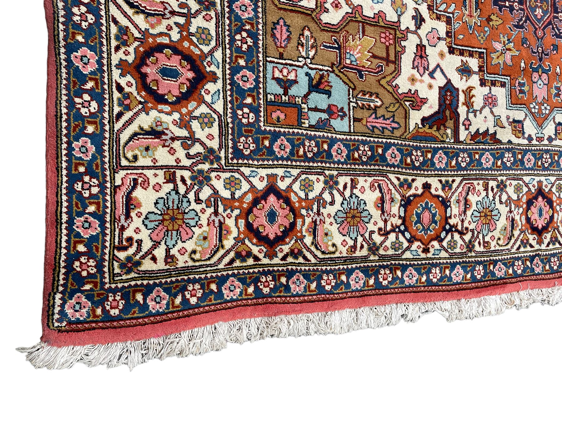 Large Persian carpet, the geometric and stylised floral medallion on rust ground field decorated with stylised plant motifs, guarded ivory border with repeating pattern