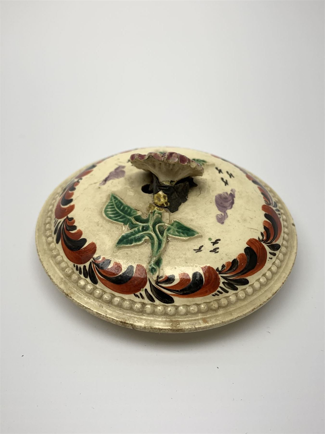 18th century creamware teapot, probably Leeds, with reeded entwined handle and floral finial to the cover, the body with hand painted polychrome decoration of figure to one side, and floral spray to the other, collectors paper label beneath inscribed Leeds Pottery, H11.5cm