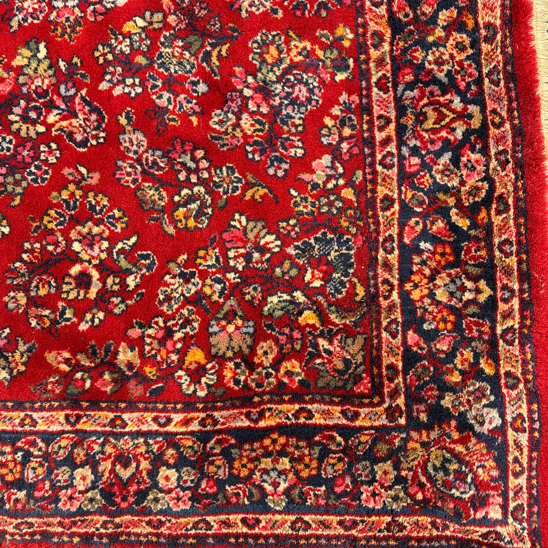 Persian Isfahan-style hand-knotted rug, crimson ground, with an intricated all-over floral spray design with palmettes and leaves, wide midnight blue main border with rosette and palmette motif, flanked by narrow guard borders  