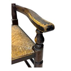 Early 19th century ash armchair, the back with winged spindles extending from a shaped top rail, above a splat of two rows of vertical spindles, with curved arms and a rush seat, raised on turned supports united by double stretchers terminating in castors
