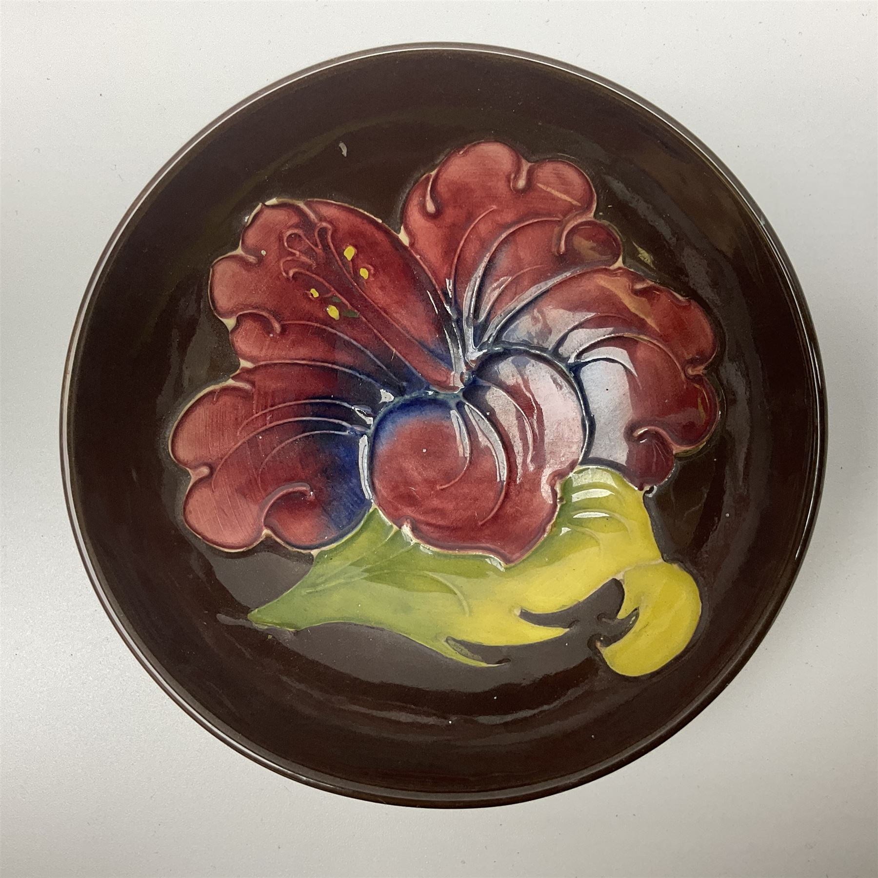 Small Moorcroft pin dish, decorated in the Hibiscus pattern with brown ground, D11cm