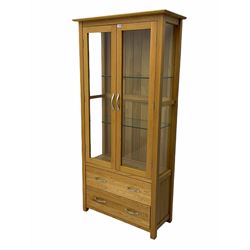 Light oak display cabinet, enclosed by two glazed doors, two drawers