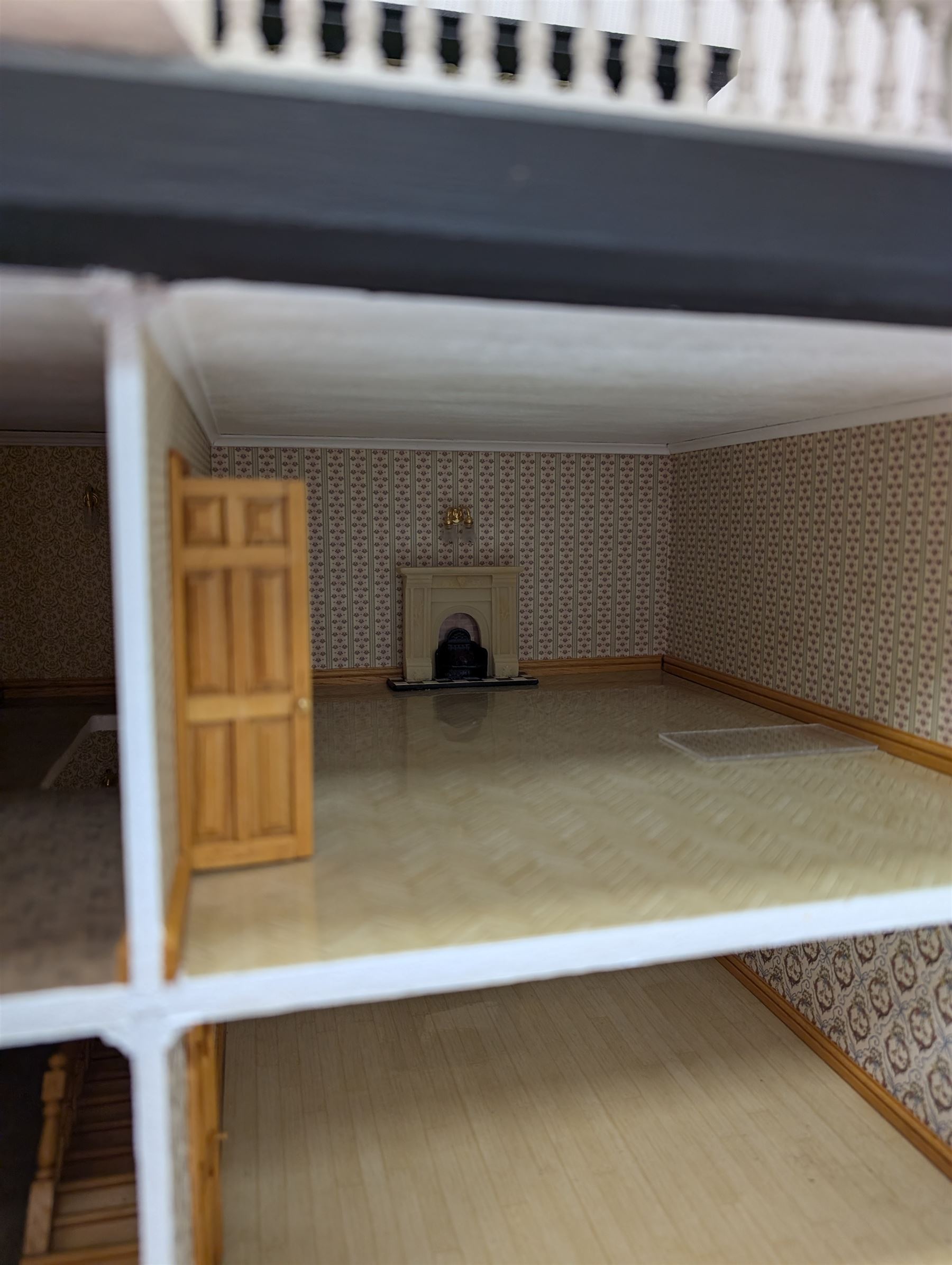 1:24 scale four-storey tudor-style dolls house, with black and white exterior, balcony garden, glazed panelled windows and wooden shingle roof, with decorated interior and wired fireplaces and lighting, H65cm, W58cm, D31cm, 