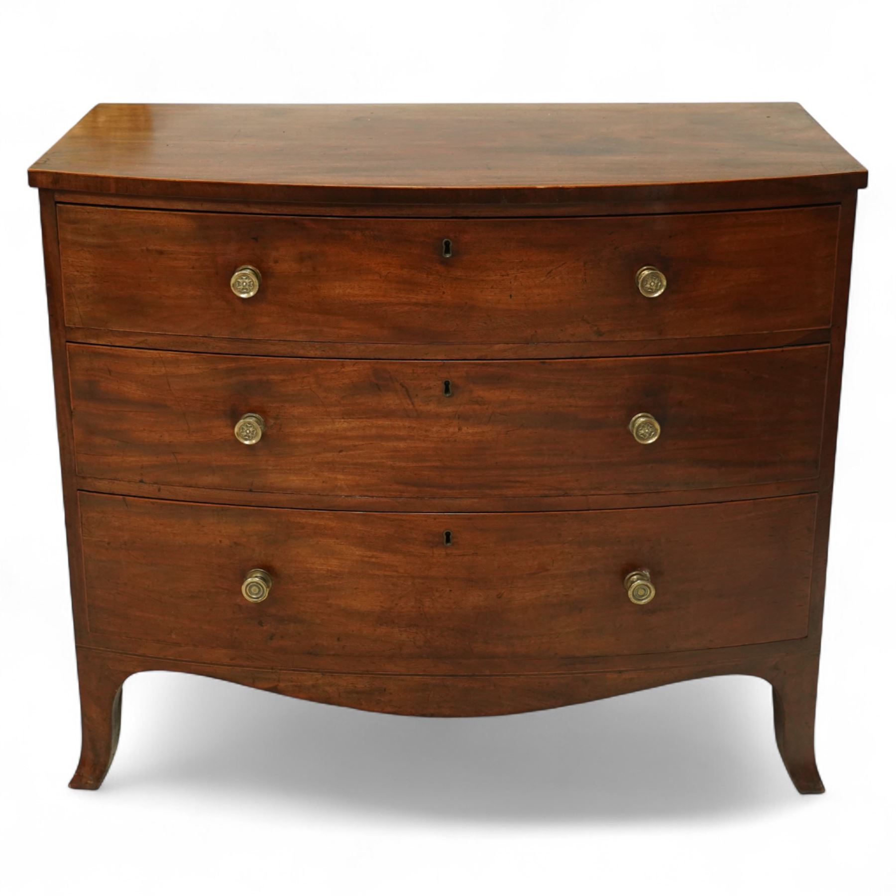 Late George III mahogany bow-fronted chest, the moulded top over three long graduating drawers fitted with turned brass knobs and brass-lined escutcheons, the shaped apron and splayed bracket supports