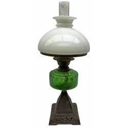 Late Victorian oil lamp, the cast metal base decorated with foliate tendrils, supporting a green glass reservoir, and opaque glass shade and clear class chimney, H60cm. 