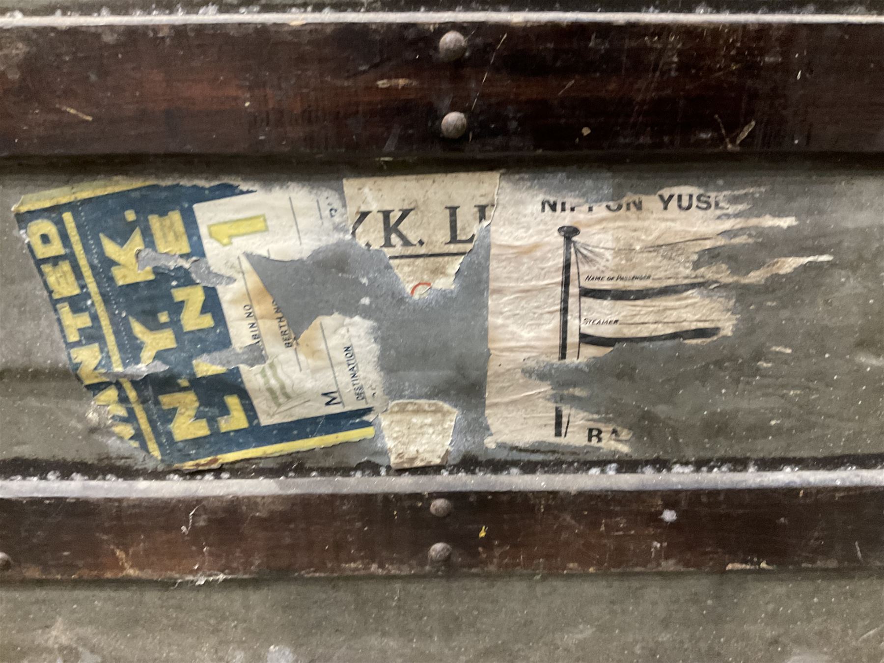 Early 20th century wood and metal bound zinc travelling trunk, hinged top with three clasps, decorated with period luggage labels