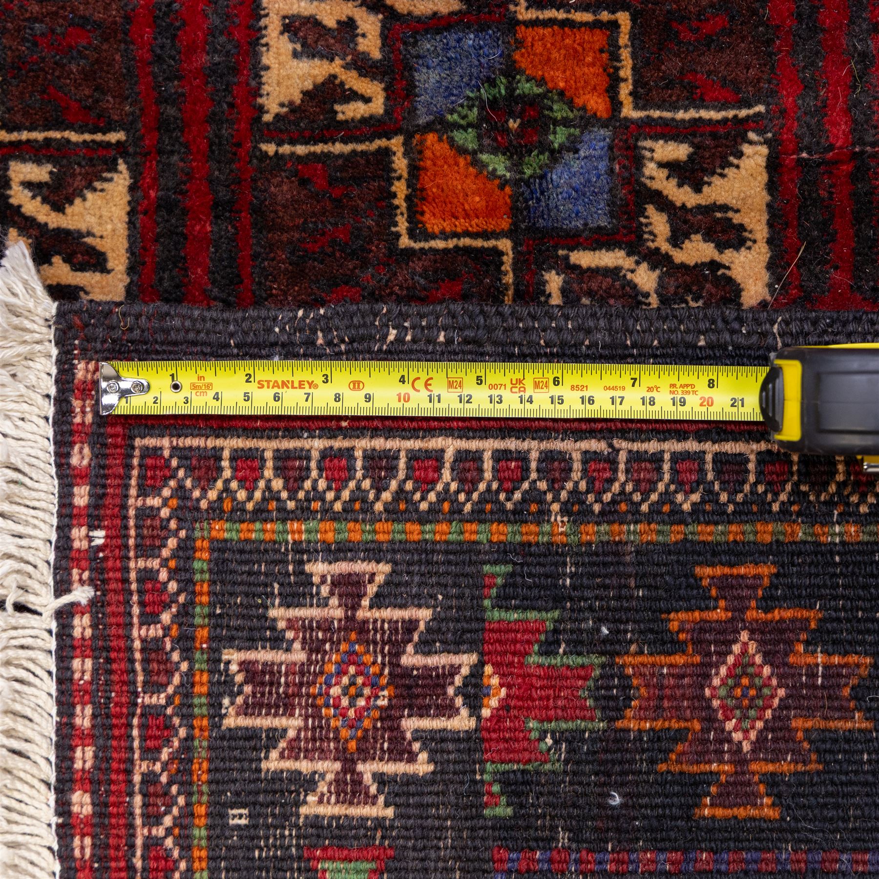 Tekke Bohara hand-knotted rug, madder red field decorated with an all-over design of repeating octagonal guls and latch-hook motifs within multiple geometric borders and cotton fringe ends 