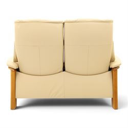 Ekornes Stressless - beech framed reclining two seater sofa, out-swept arms over tapering supports, upholstered in beige leather