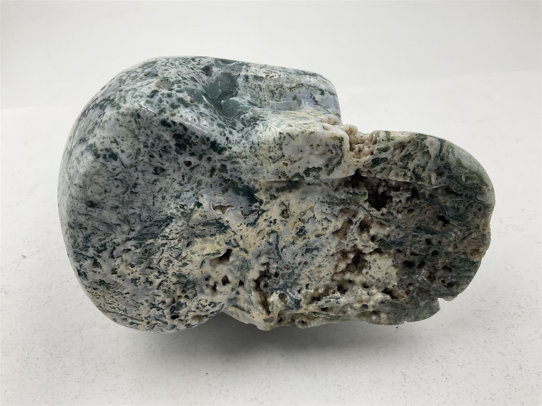 Carving of a skull in moss agate, H9cm, L12cm 