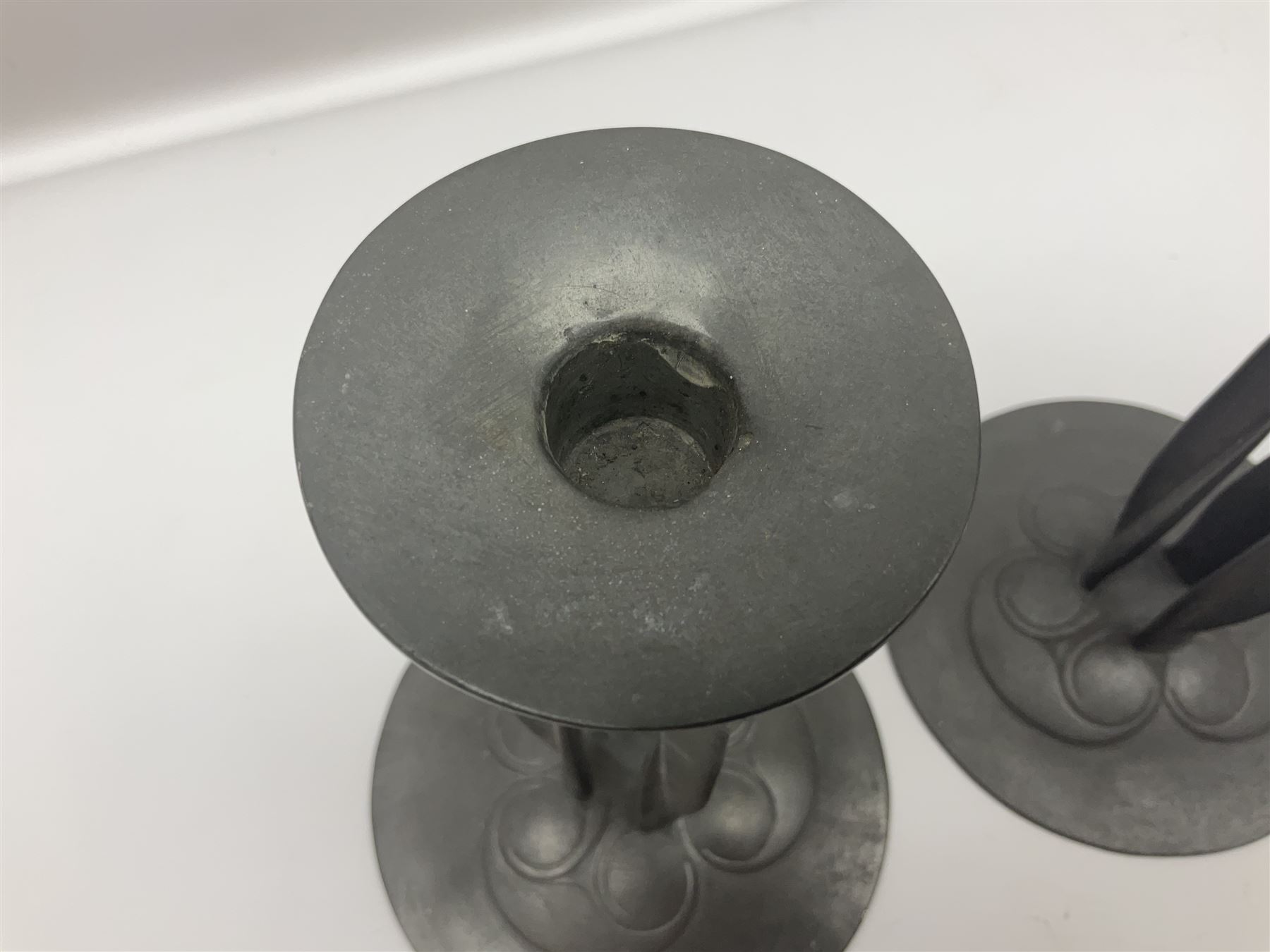 Pair of Solkets English pewter candlesticks, the bud shaped sockets raised upon three angular fin supports and a slightly domed circular base with cast stylised foliate decoration, H23cm