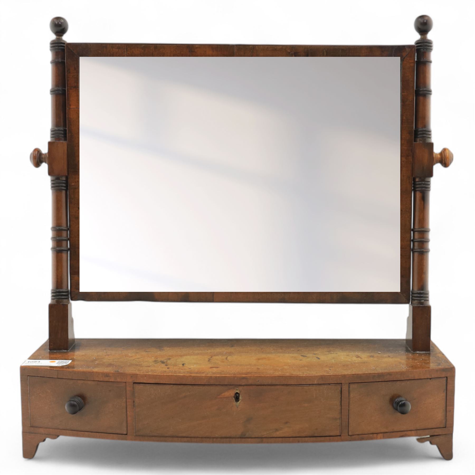 19th century mahogany swing mirror, rectangular frame on turned supports with ball finials, bow front base fitted with three drawers and ebony knob handles, raised on shaped feet