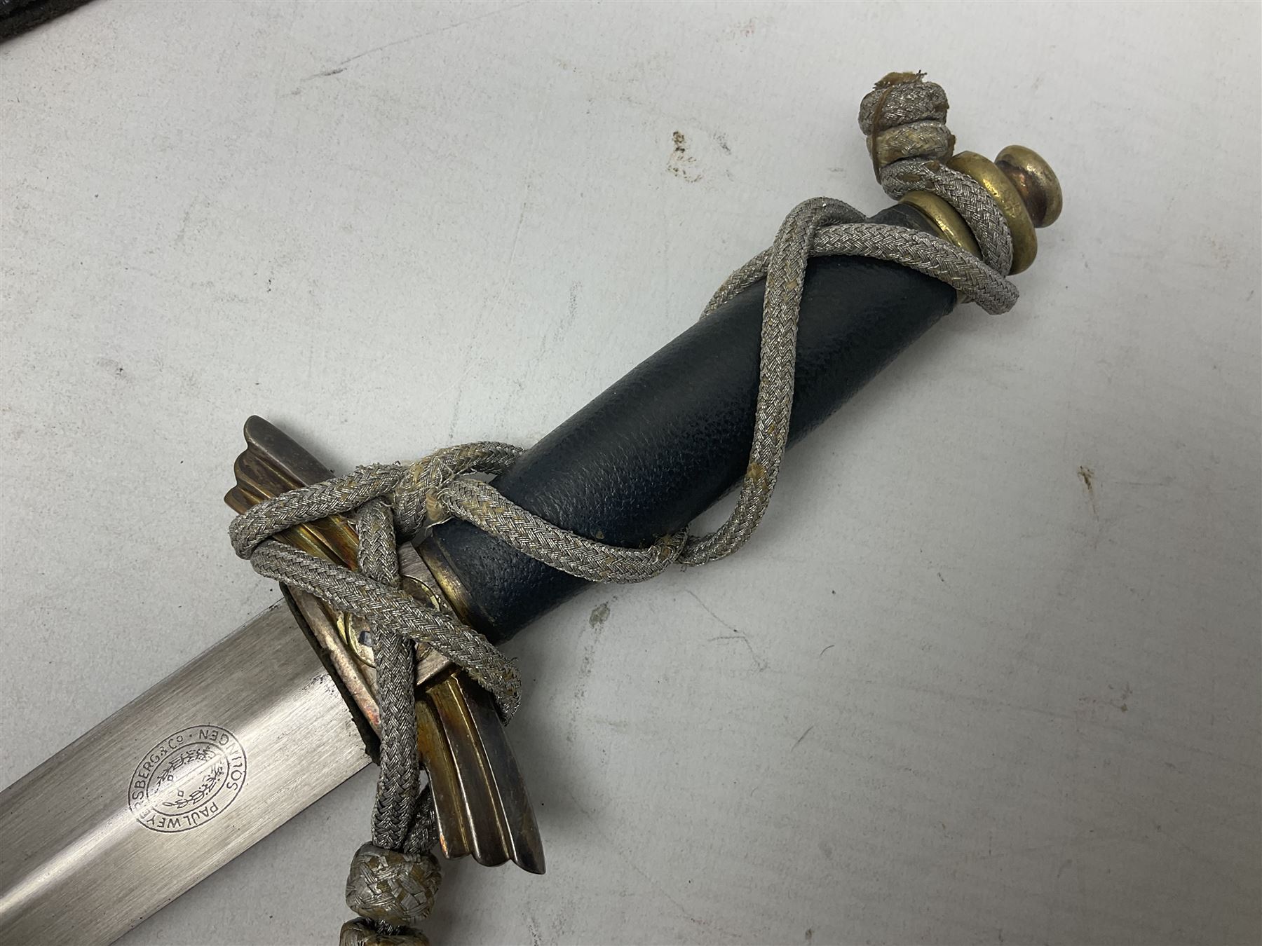 German Paul Weyersberg & Co Solingen DLV flyers dagger with 18cm steel blade, plated brass/tombac downswept cross-piece and pommel and leather covered grip, in leather and plated brass/tombac scabbard with leather hanger strap and silvered knot L35cm overall. Auctioneer's Note: After WWI Germany was forbidden an air force by the Treaty of Versailles however the Deutscher Luftsport-Verband (German Air-sport Association) was formed in March 1933 from various sports flying clubs and had branches for aeroplane, gliding and balloon flying. Under cover of the sporting DLV, many future Luftwaffe pilots trained to fly. DLV was embodied with the NSKK in March 1935 and on 1st March 1937 Luftwaffe was formed.