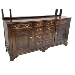 George III oak dresser, the plate rack with shaped frieze over three tiers, the base fitted with four central graduating drawers, the heavily moulded edges designed to appear as eight short drawers, flanked by single drawer over panelled cupboard, on bracket feet