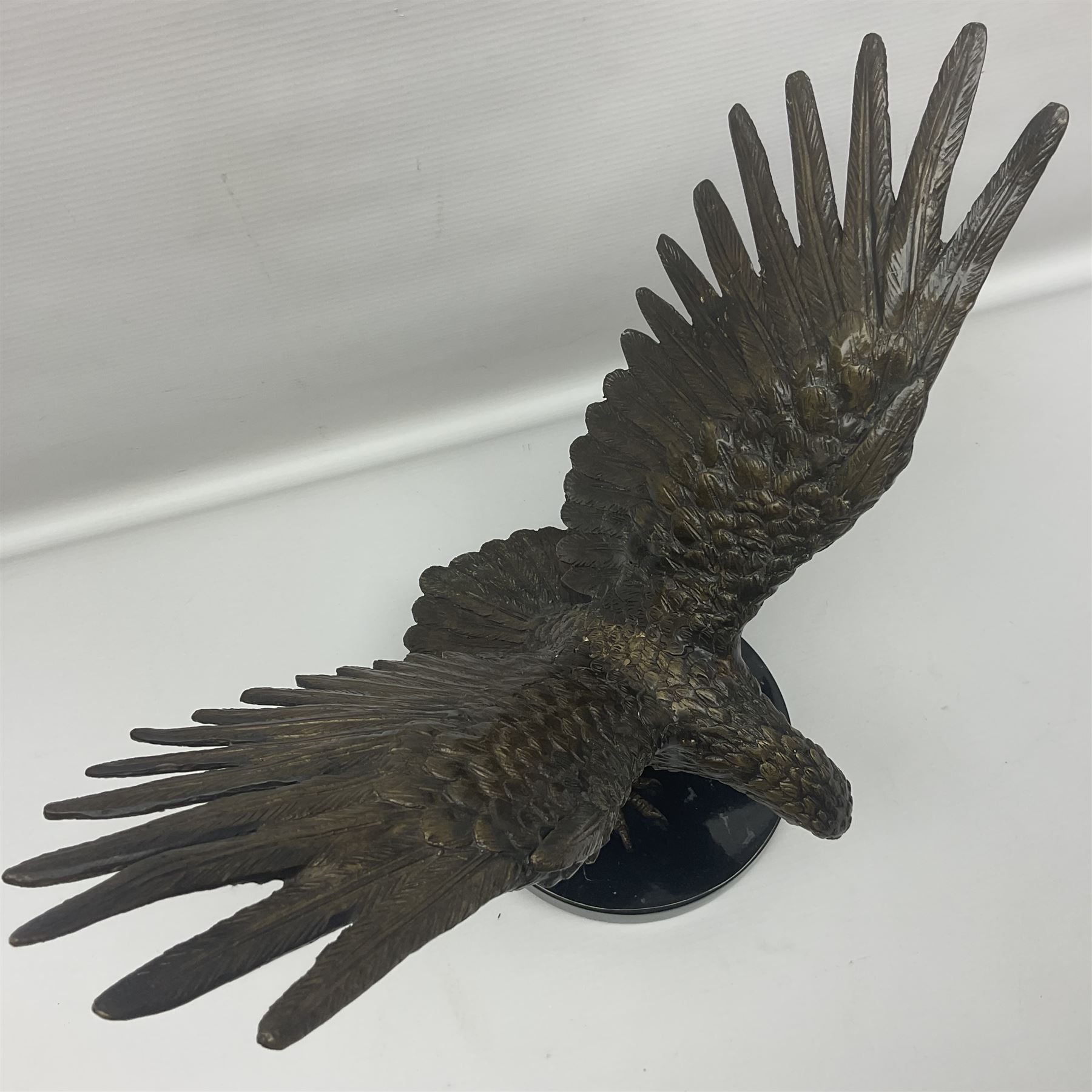 Bronze eagle, modelled in a standing position with wings spread, raised on a black veined marble circular plinth base, H29cm
