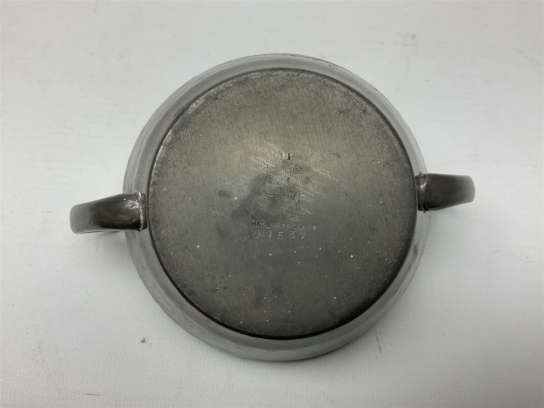 Liberty & Co Tudric pewter three piece tea service, comprising teapot with woven reed handle, twin handled open sucrier, and milk jug, each of squat form with planished finish, each impressed beneath Tudric Pewter Ware 01537 Made in England, together with a matched unmarked tray