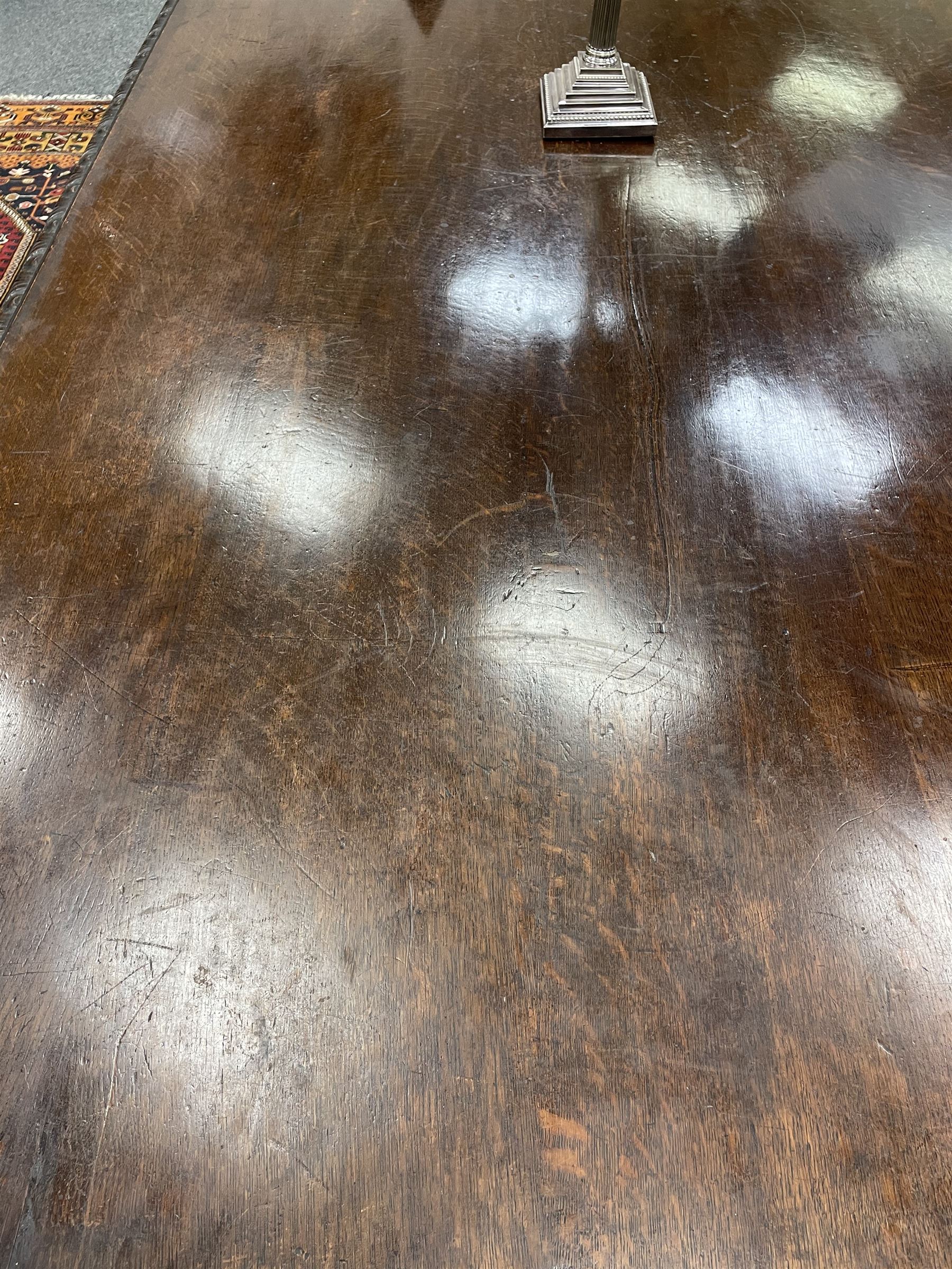 Large 19th century carved oak library table, the rectangular top with lunette carved edge over cartouche panelled and carved  scroll frieze, the central tapering rectangular support relief carved with masks and garlands, on four carved seated lion supports at each corner, on flat angular stretcher with recessed castors stamped ‘Bartholomew & Fletcher, London’