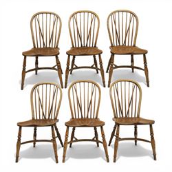 Traditional elm and beech Windsor dining chairs, each with hoop back and turned spindles over a shaped solid seat fitted with loose floral upholstered cushions, raised on turned tapering supports united by crinoline stretchers
