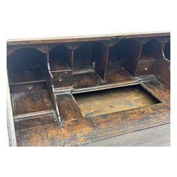 George III oak bureau, sloped fall-front enclosing a fitted interior with pigeonholes, small drawers, and a central compartment, over two short and two long drawers, brass escutcheons and drop handles, raised on bun feet