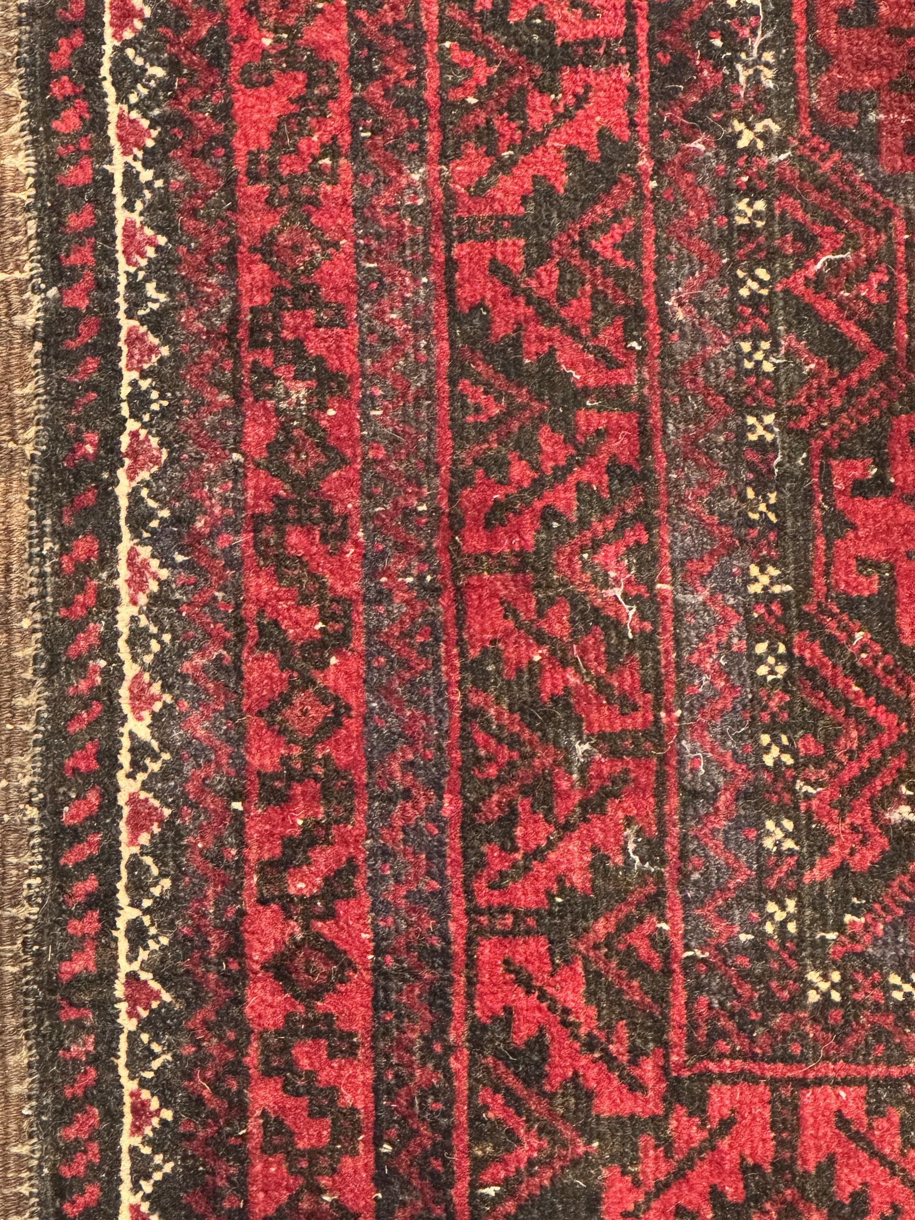 Turkoman red ground wool rug, the field with a repeating pattern of Tekke gul motifs in dark brown and red (195cm x 98cm); Afghan Bokhara red ground wool rug, central field with repeated geometric octagonal gul motifs, surrounded by multiple borders with stylised diamond and triangular patterns (127cm x 181cm)